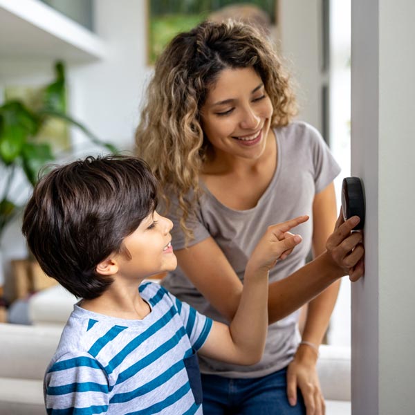 mother and son adjusting thermostat at home