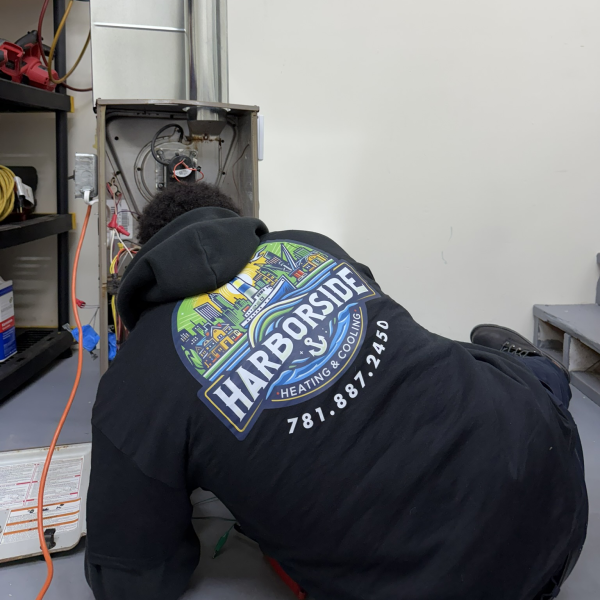 HVAC technician wearing Harborside hoodie inspecting working on HVAC repair